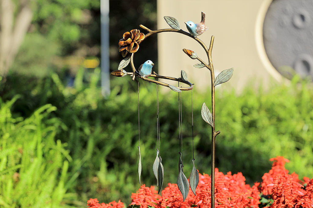 cast metal bluebirds seated on whimsical branch of leaves and flowers. Staked windchime