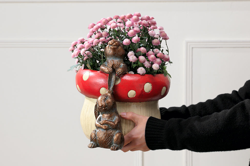 red spotted mushroom planter with two playful bunnies tugging at ones ears 