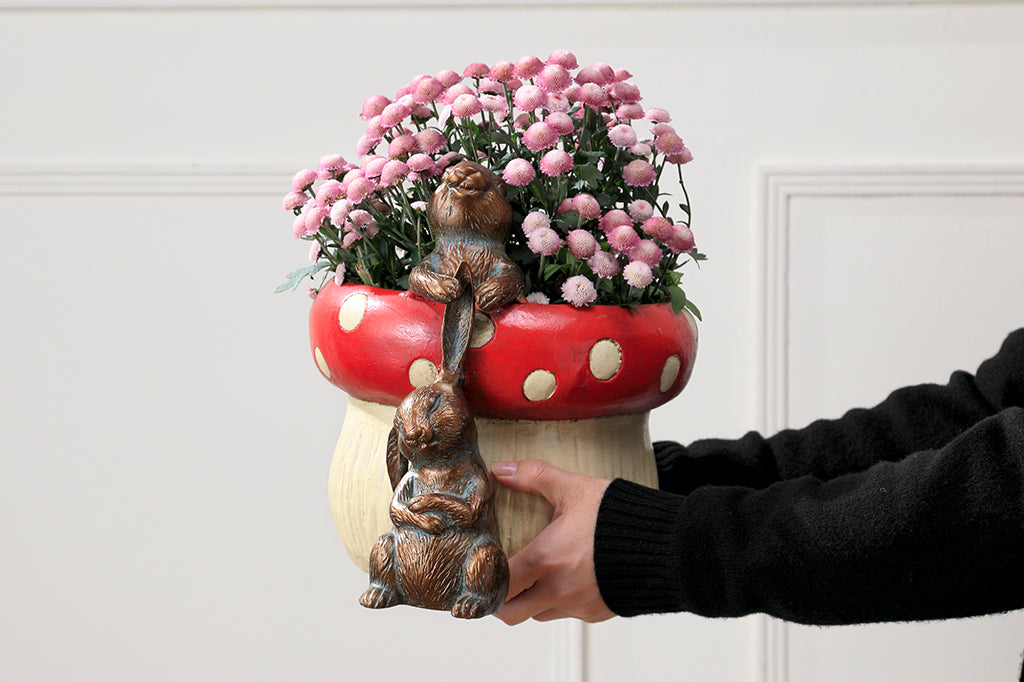 red spotted mushroom planter with two playful bunnies tugging at ones ears