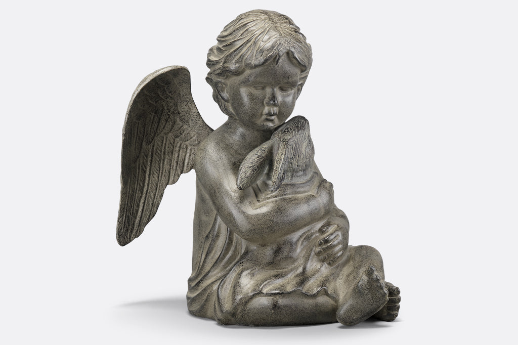 Cast metal cherub with wings holding bunny in blanket face right