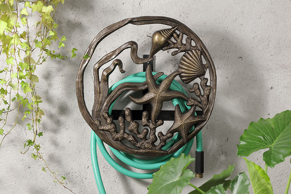Under The Sea Hose Holder mounted on a wall and holding a green hose