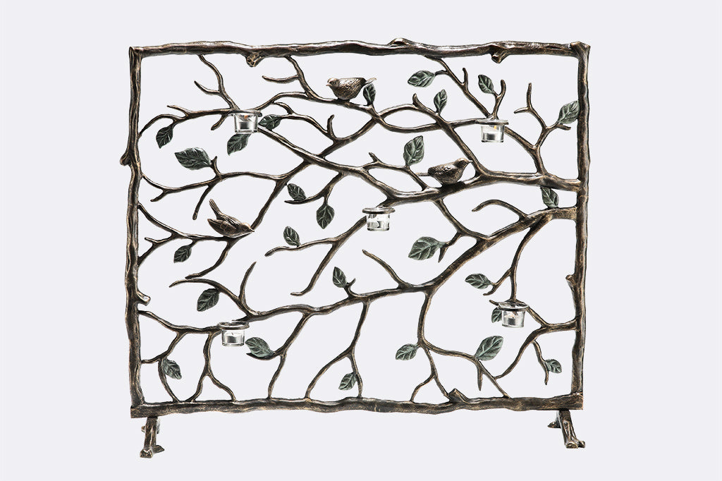 Decorative fireplace grill features birds on branches with green leaves; holds 5 tealights in glass cups