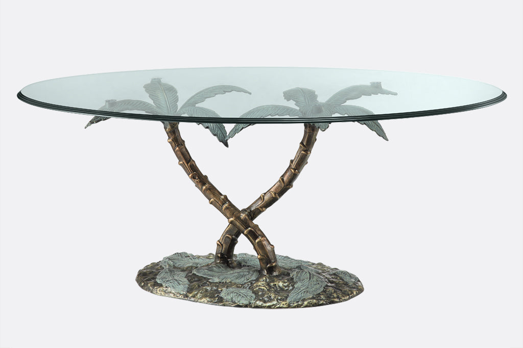 cast metal and glass table held up by palm tree