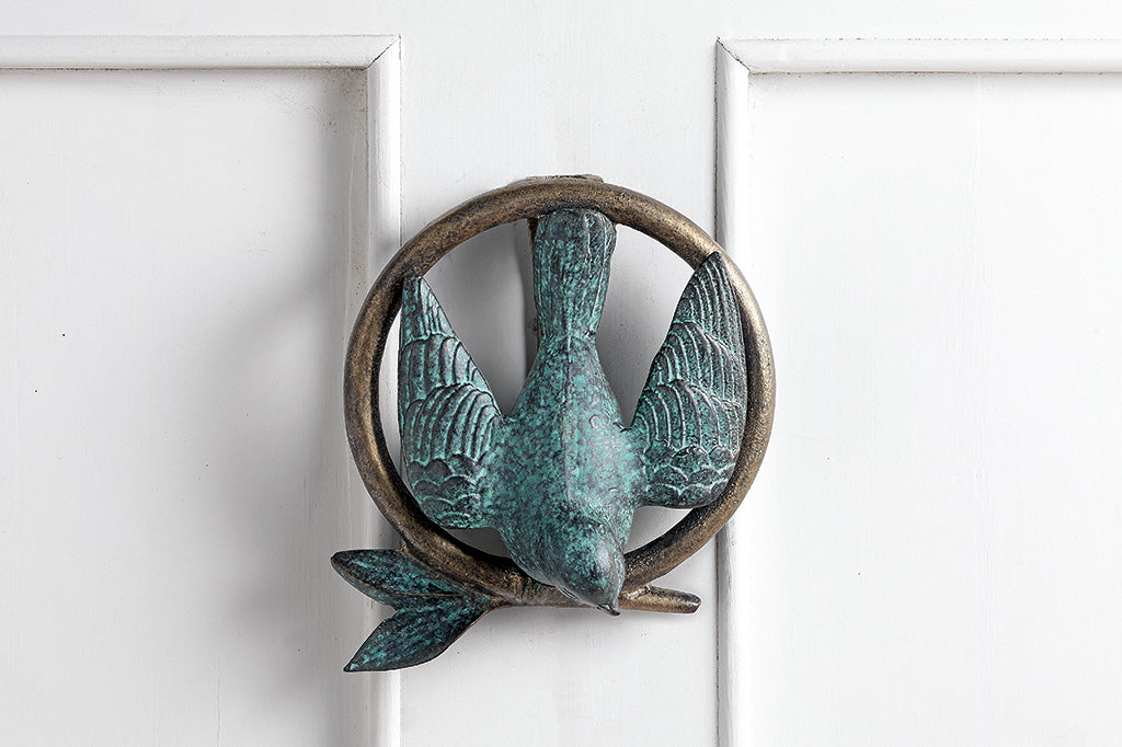 Door knocker shown on white door; peaceful dove and branch within a circle