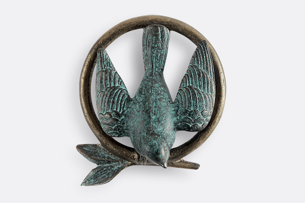 Door knocker shown on white door; peaceful dove and branch within a circle. Dove and leaves are green.