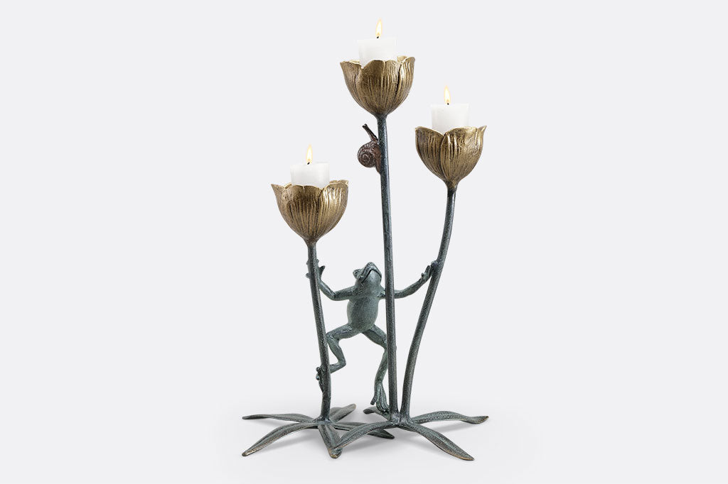 A curious frog watches a snail on a flower stem in a cast metail sculpture and votive candle, holds three candles in the blossoms holder