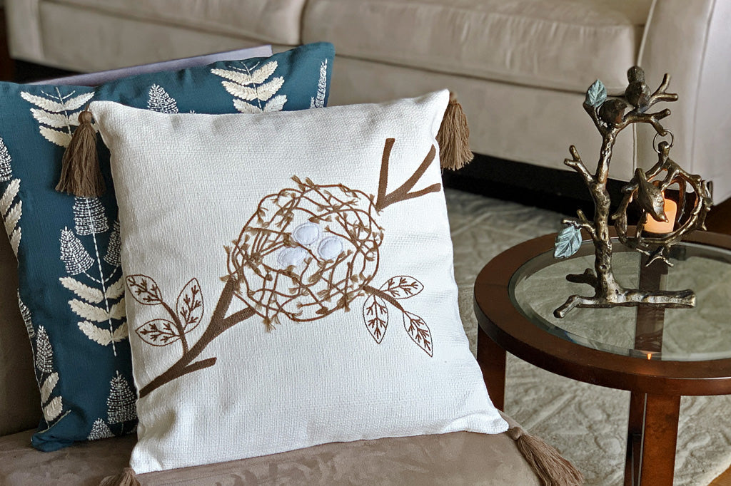 Picture of tea light candle holder on a glass table in a living room next to couch and pillows