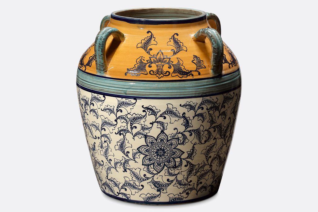 hand painted and thrown ceramic pot with mediterranean prints done in vivid yellow-orange, light and dark blue with floral print on white