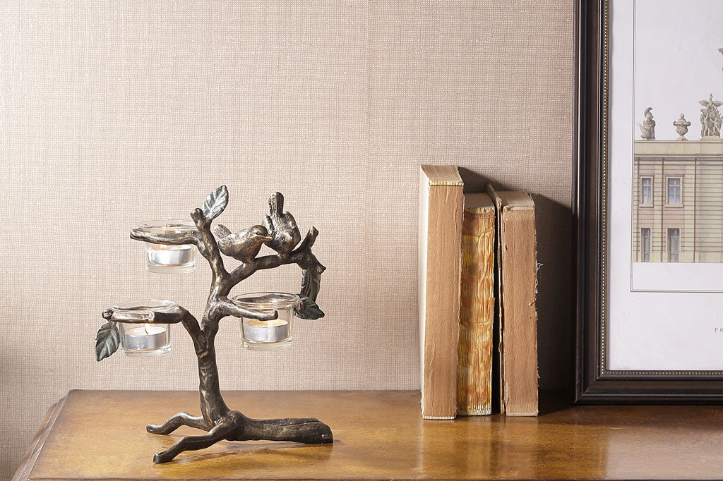 small bird and branch table candelabra with 2 birds, holds 3 tealights in glass cups shown on desk near books and framed art