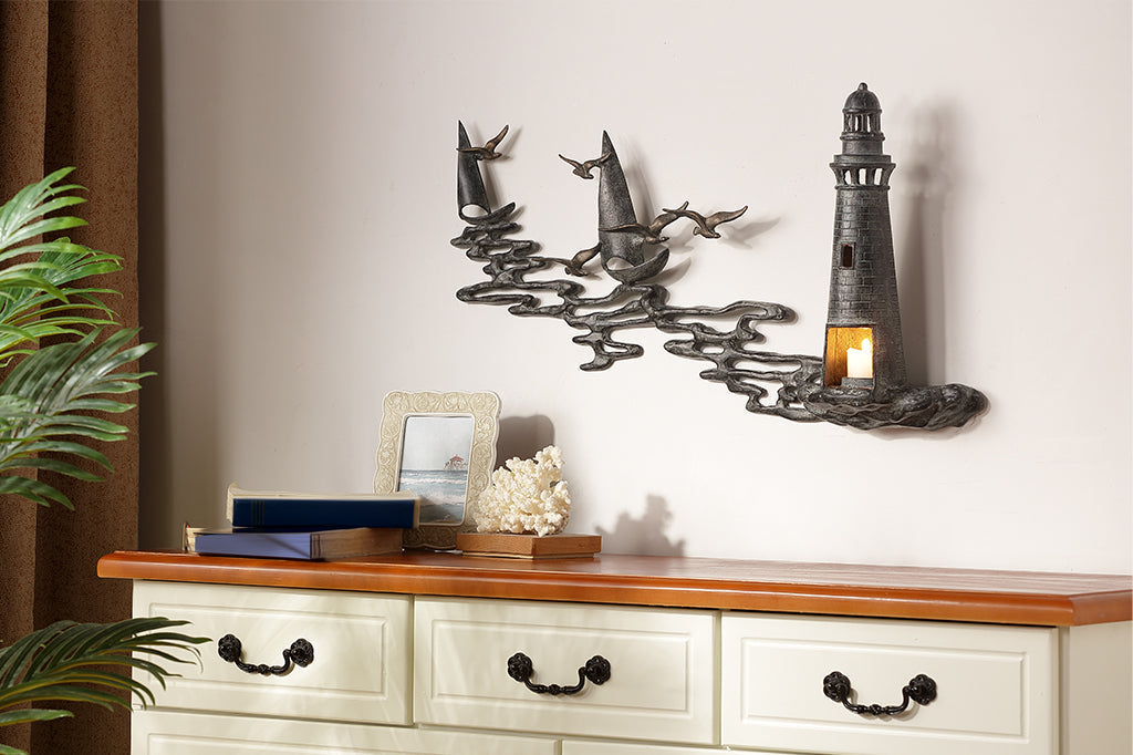 Wall art Votive holder cast metal sculpture of Lighthouse by the sea with 2 sail boats on the wall above a bedroom dresser