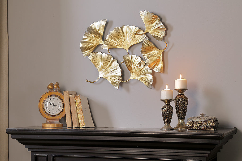 wall art of ginkgo gold leaves in flurry of 6, shown above fireplace near gold clock and candlesticks