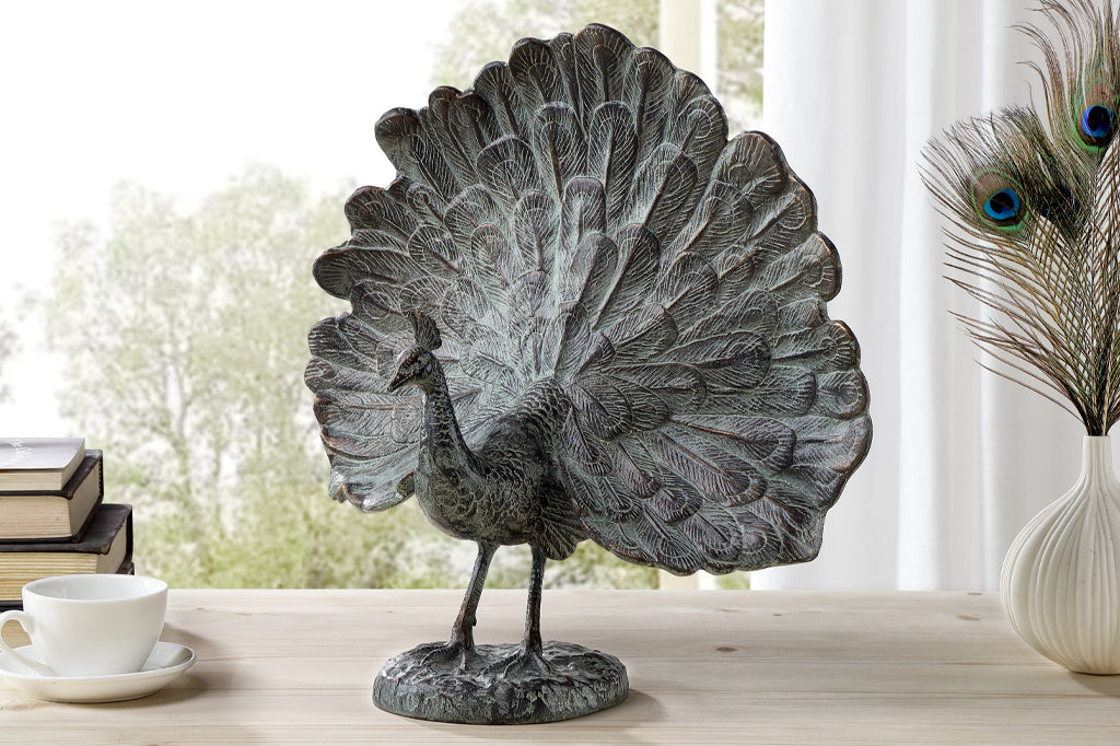 cast metal peacock with feathers fanned out set on counter top