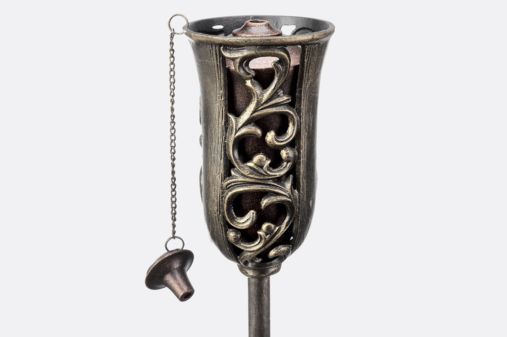 cast metal oil torch with swirling details and cap for oil torch wick