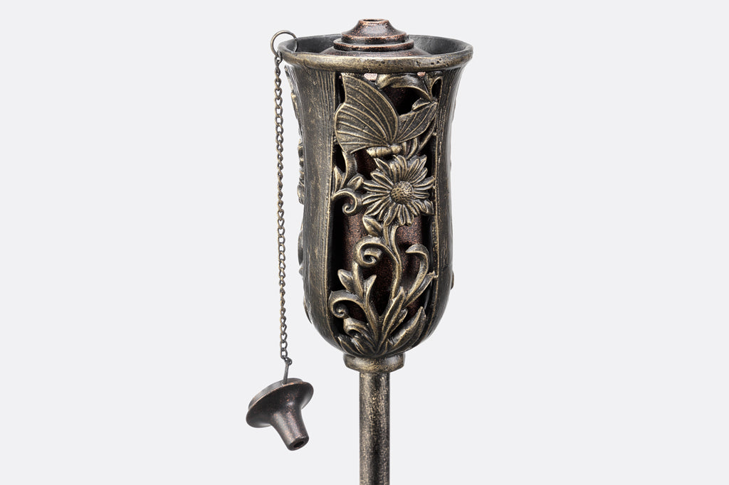 cast metal oil torch with butterfly and flower detailing