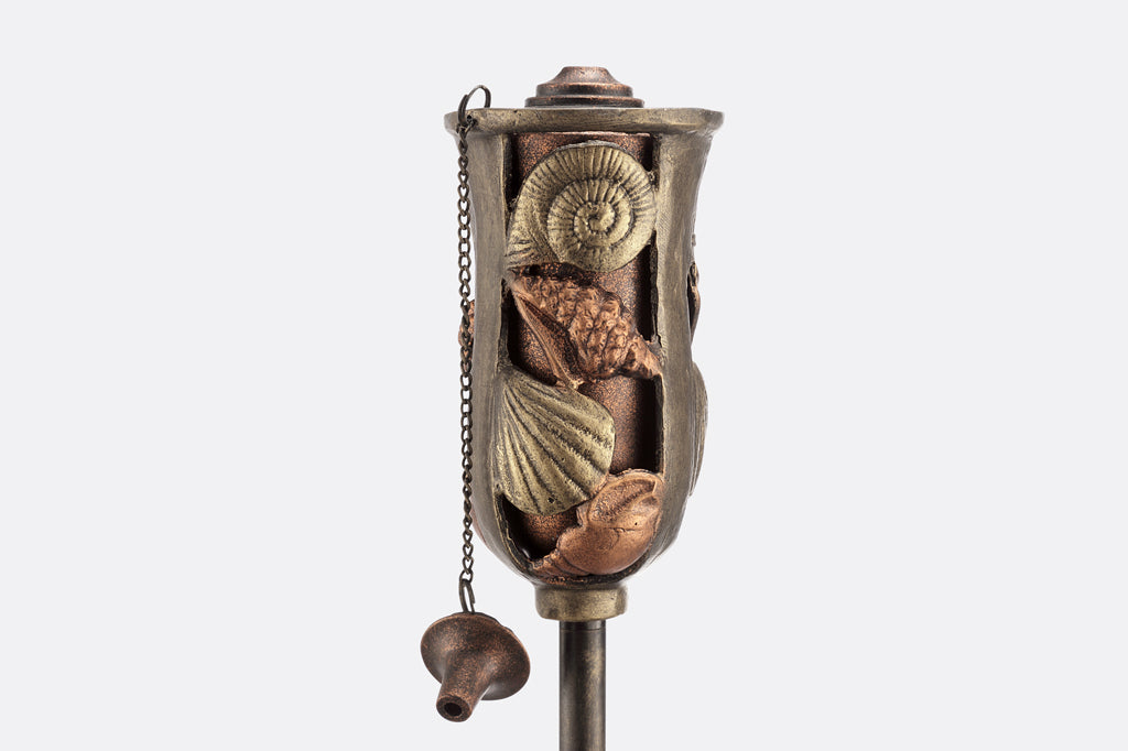Cast metal oil torch with shell illustration detail