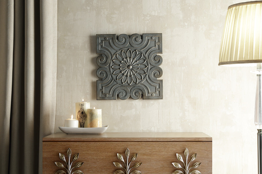 cast metal geometric wall tile with floral design in center hanging on wall above cabinet