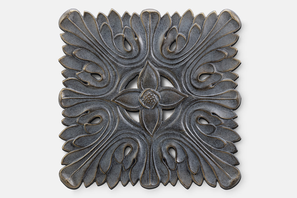 cast metal wall plaque tile with a flower detailing in the middle surrounded by swirls