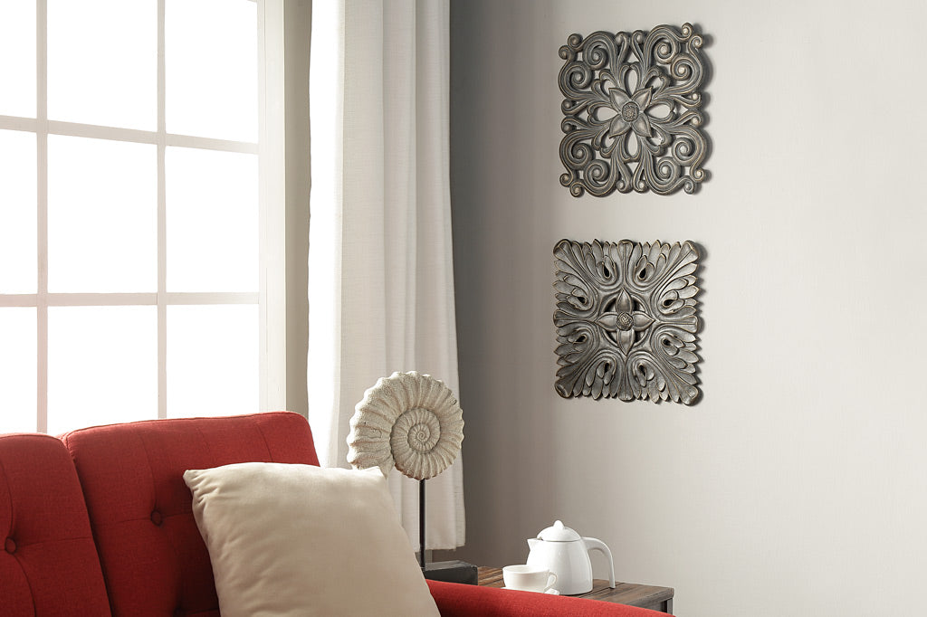 cast metal wall tile placed on wall in a grouping of two next to red couch
