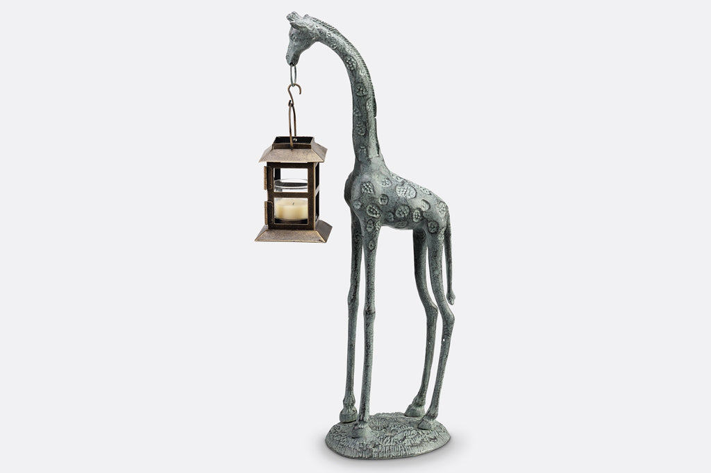 cast metal giraffe holding lantern in mouth sculpture