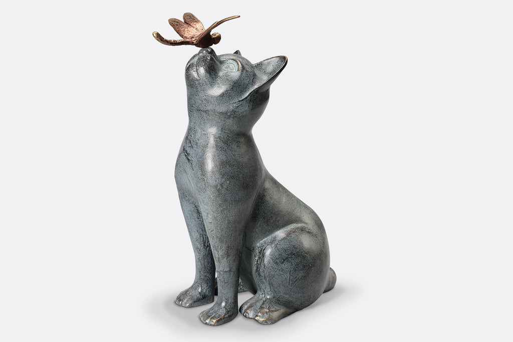 cast metal cat sculpture looking up with dragonfly landing on cat's nose