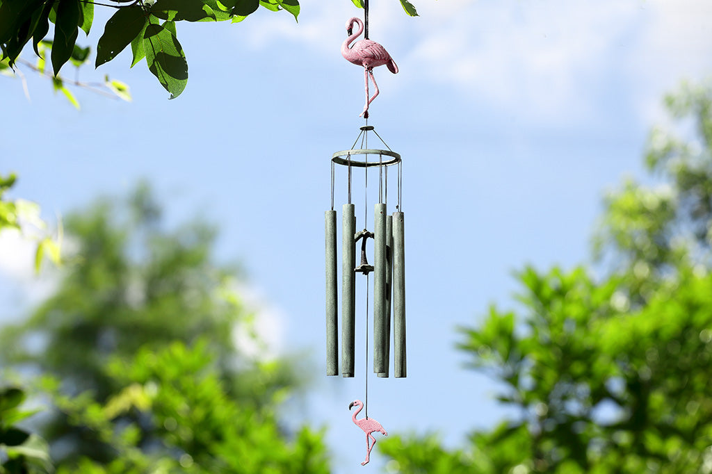 flamingo themed wind art shown hanging from tree branch on sunny day
