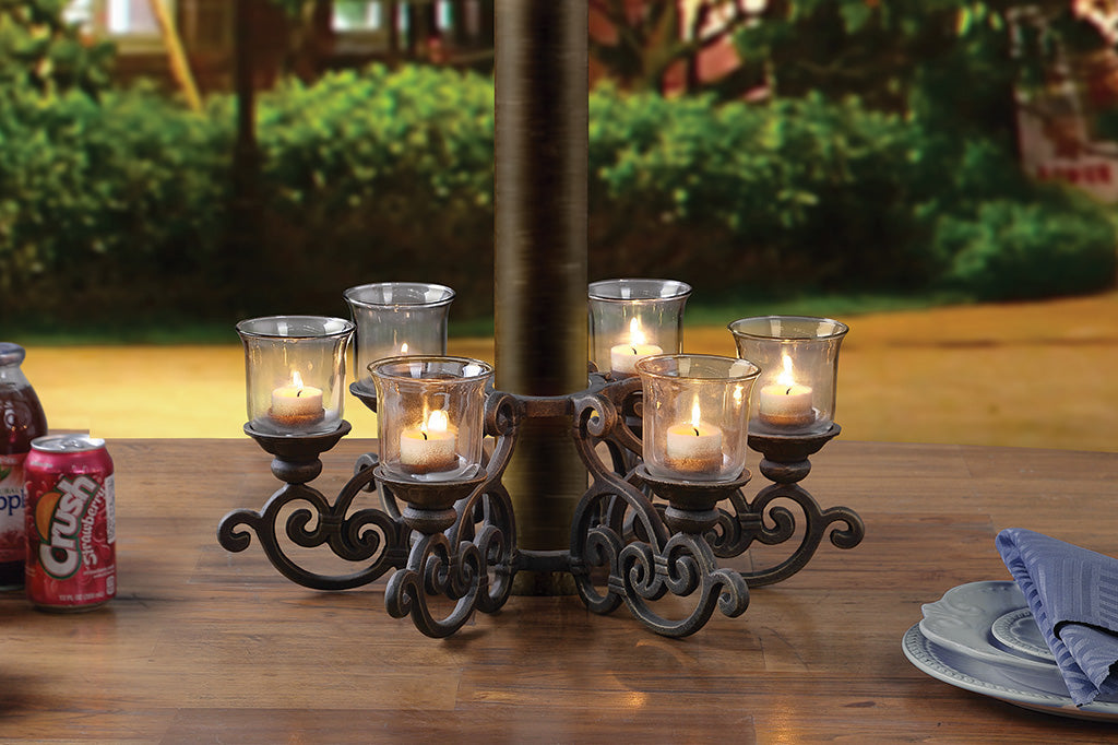 candelabra with candles set around umbrella stand on picnic table