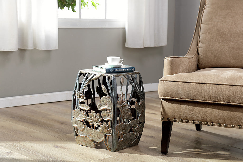 cast metal lotus flowers and cattails squared garden stool, floral design on all four panels of stool. Shown indoors next to an arm chair