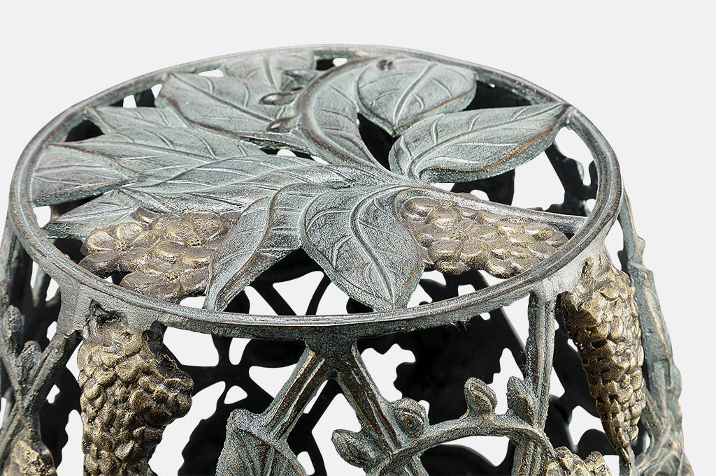 Cast metal garden stool of lattice design and vining blossoms- closeup view of leaf and blossom sculpted seat top
