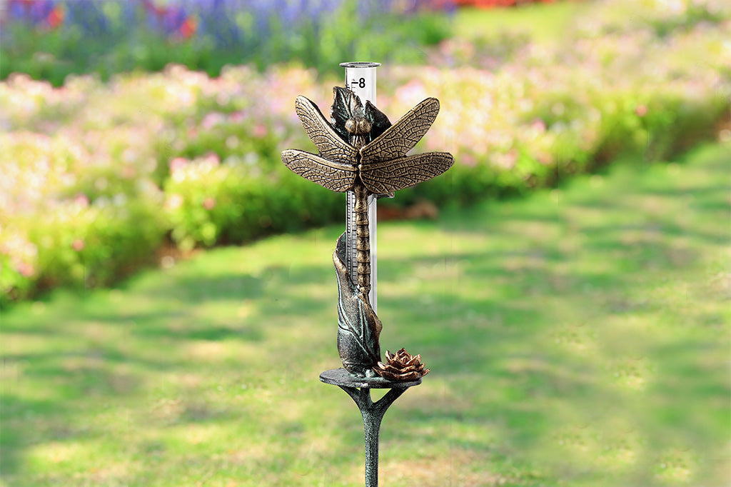 dragonfly sculpted motif on rain catcher, small leaf and blossom accents; shown with yard in background