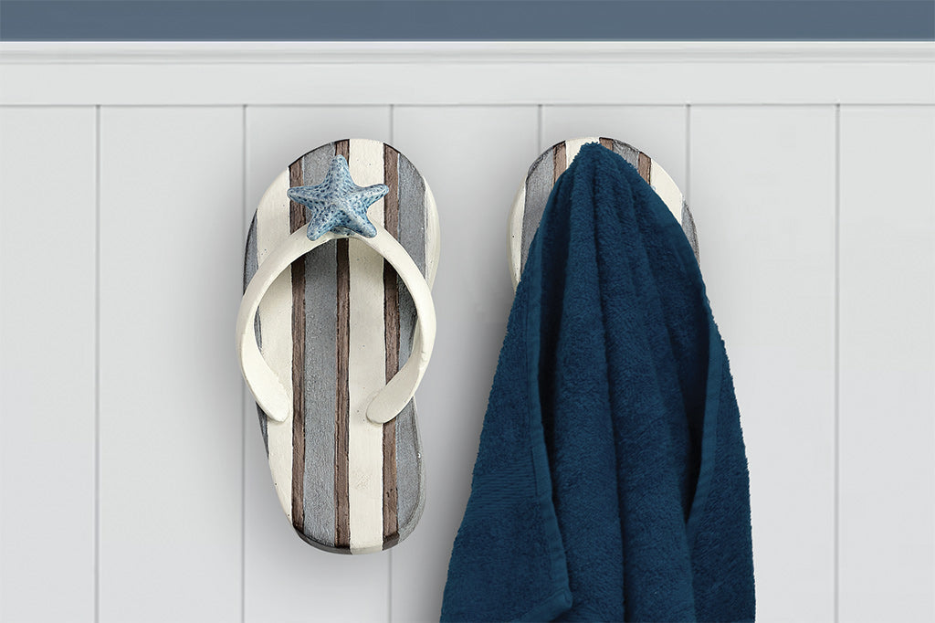 Wall hooks shaped like pair of blue and white striped flip flops with sea shell motif - one of the pair holds a blue bath towel #color_stripe