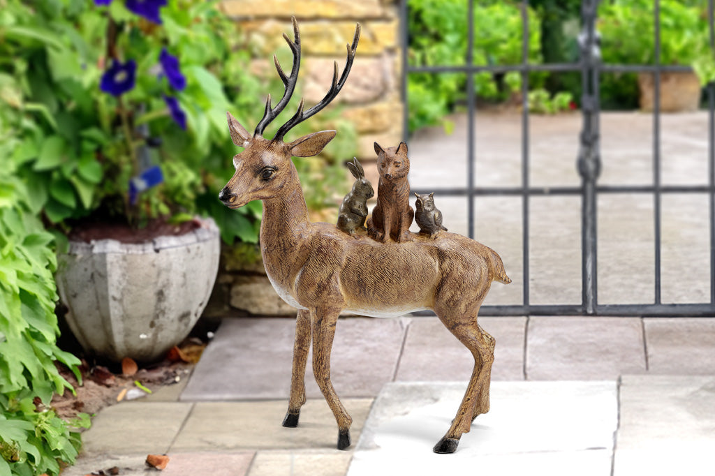A sculpture in garden courtyard of a bunny, fox, & owl cozy up together on a friendly deer