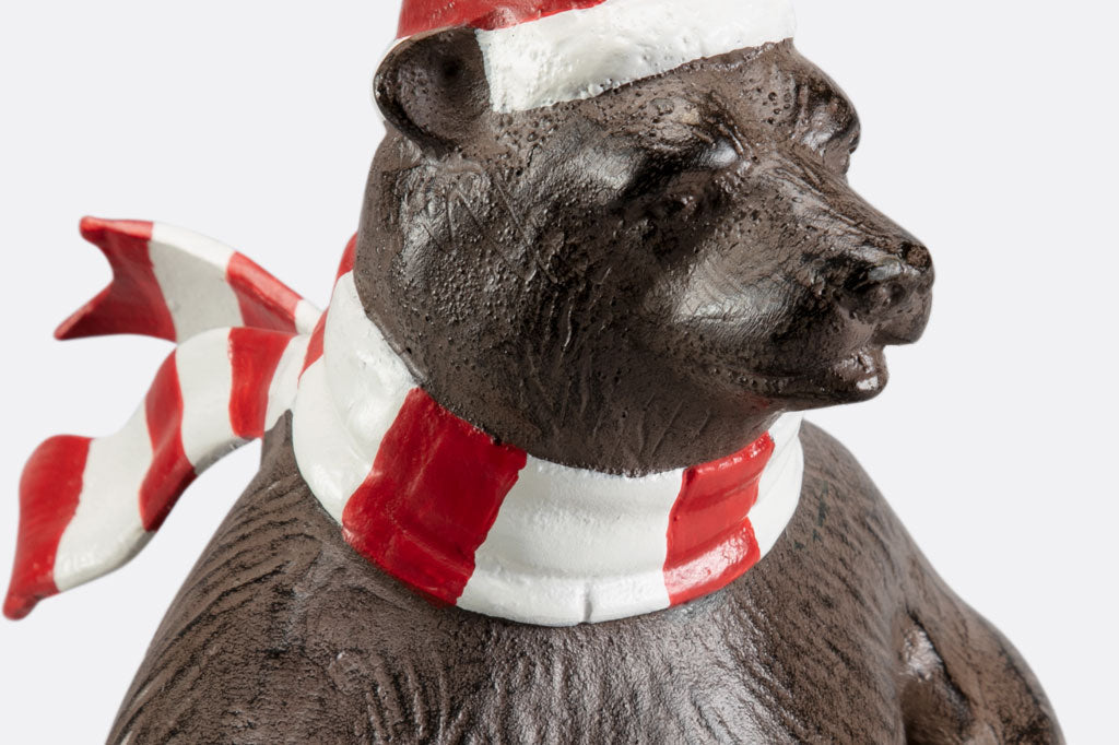 A bear wearing a santa hat and striped scarf is skiing as part of a holiday table display