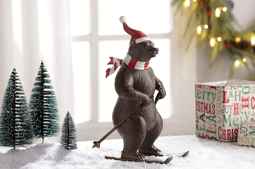 A bear wearing a santa hat and striped scarf is skiing as part of a holiday table display