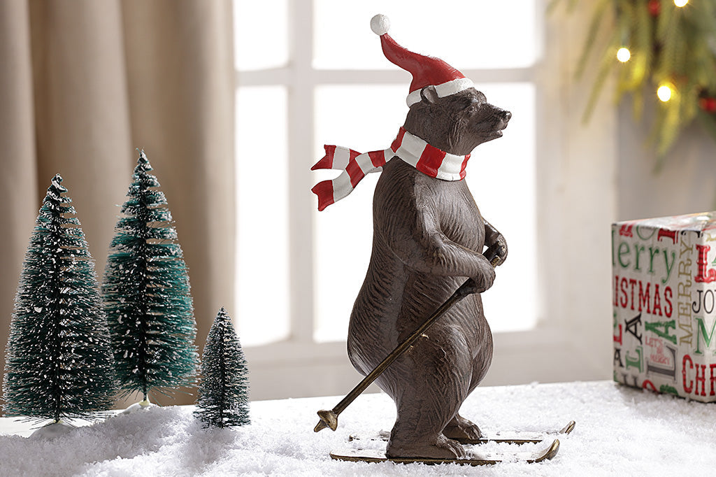A bear wearing a santa hat and striped scarf is skiing as part of a holiday table display