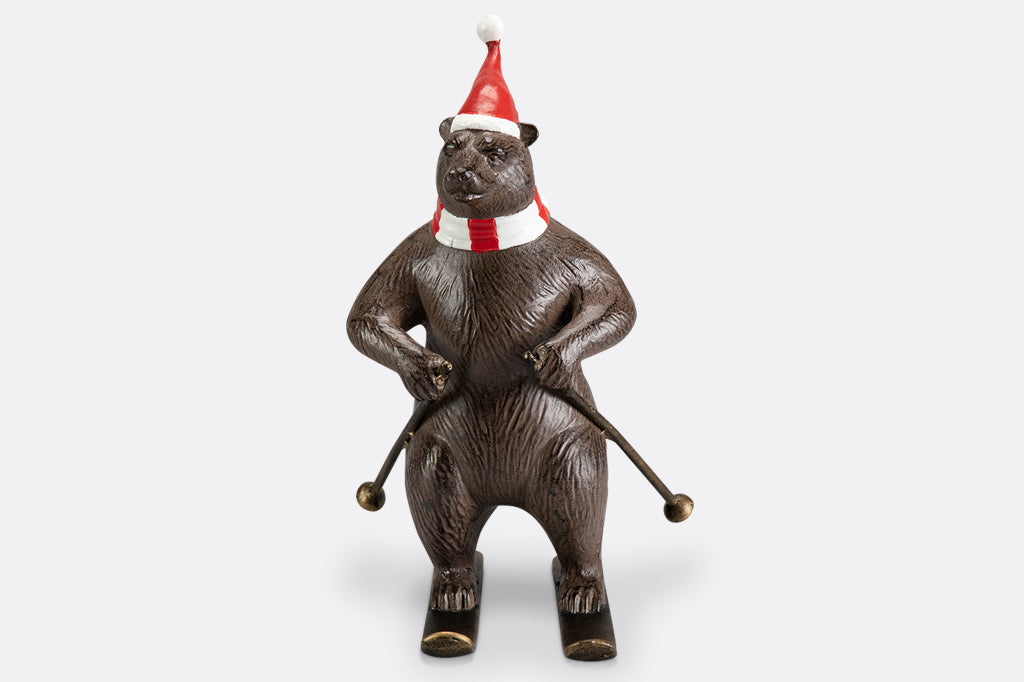 A bear wearing a santa hat and striped scarf is skiing as part of a holiday table display