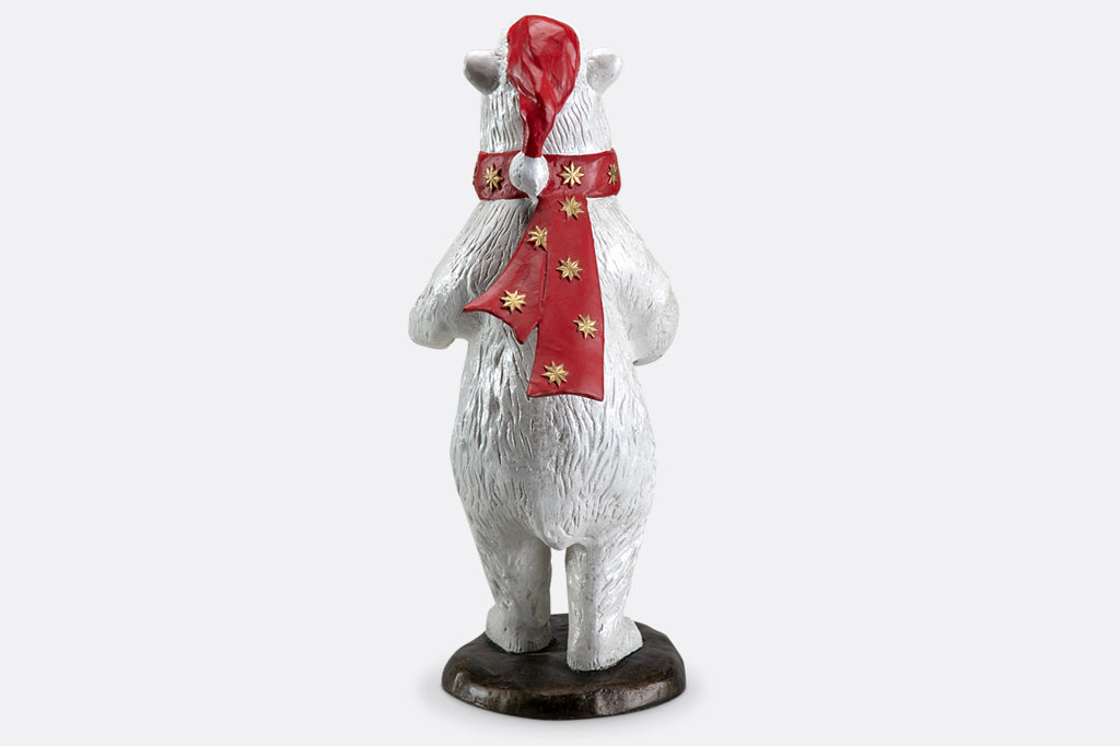 Polar bear wearing had and scarf holding wreath sculpture
