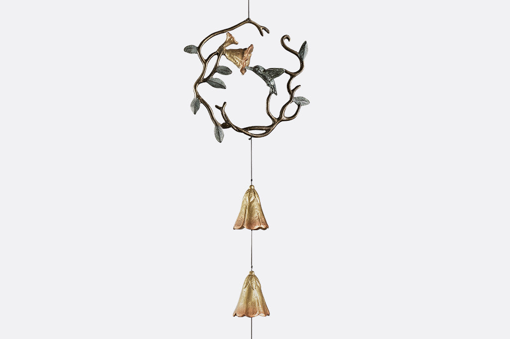 sculpted metal wind art with motif of encircled lily and hummingbird with 3 lily blossoms suspended below with a hummingbird pendant