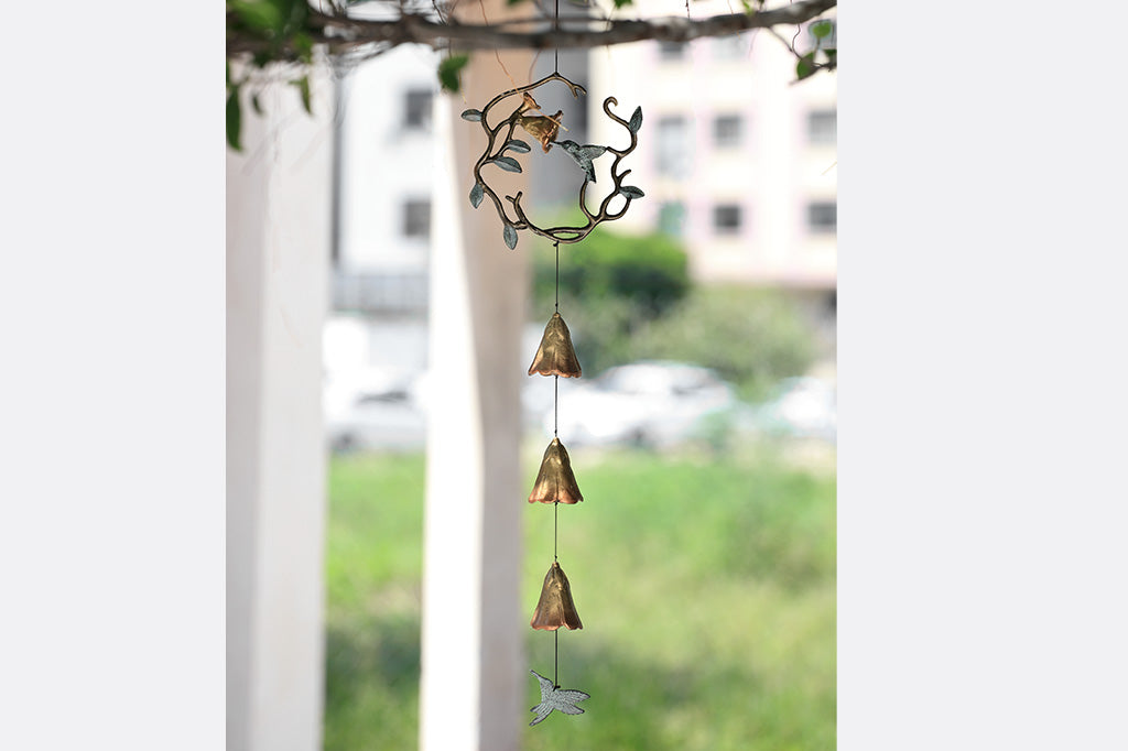 sculpted metal wind art with motif of encircled lily and hummingbird with 3 lily blossoms suspended below with a hummingbird pendant