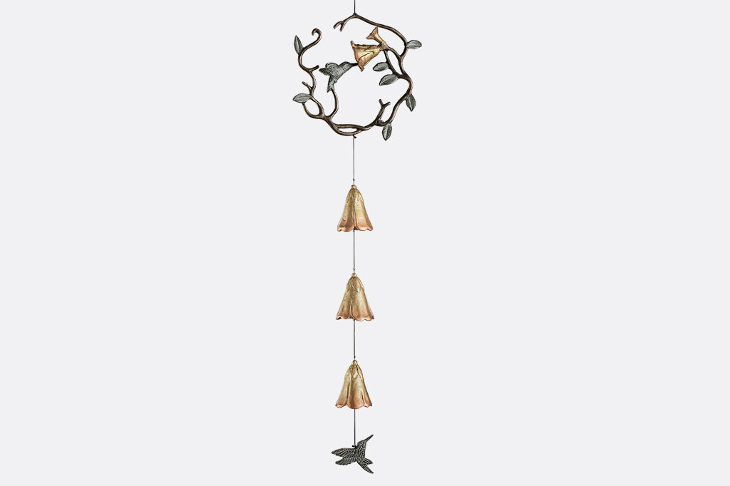 sculpted metal wind art with motif of encircled lily and hummingbird with 3 lily blossoms suspended below with a hummingbird pendant