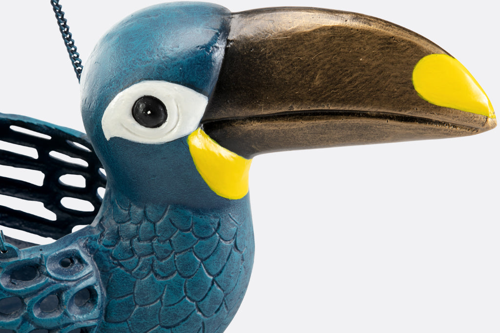 Close up of cast metal toucan hanging planter, blue toucan with gold and yellow beak. Holding red and green succulent plant