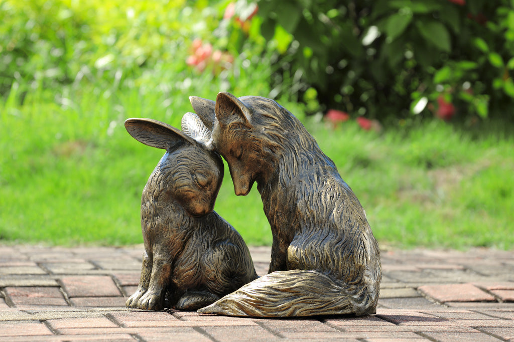 Garden sculpture of fox and rabbit tenderly nuzzling in a garden