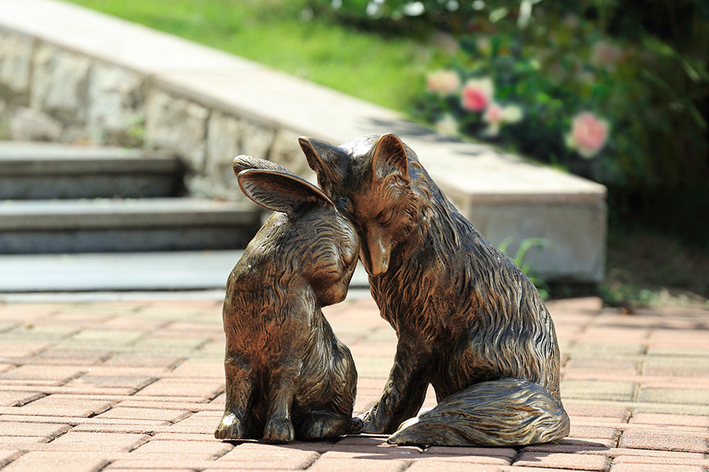 Garden sculpture of fox and rabbit tenderly nuzzling