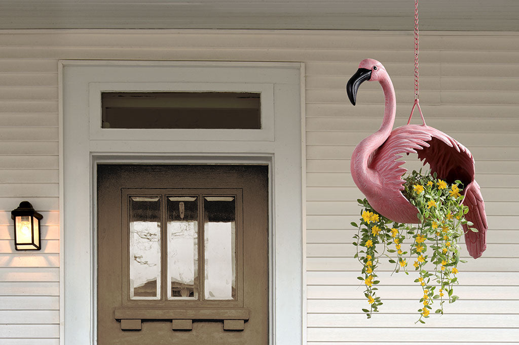 hanging planter designed for plants to be inserted into a flamingo shaped body. shown by front door of residence