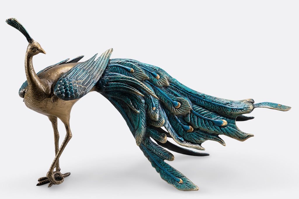 cast metal peacock with blue feathers standing proudly