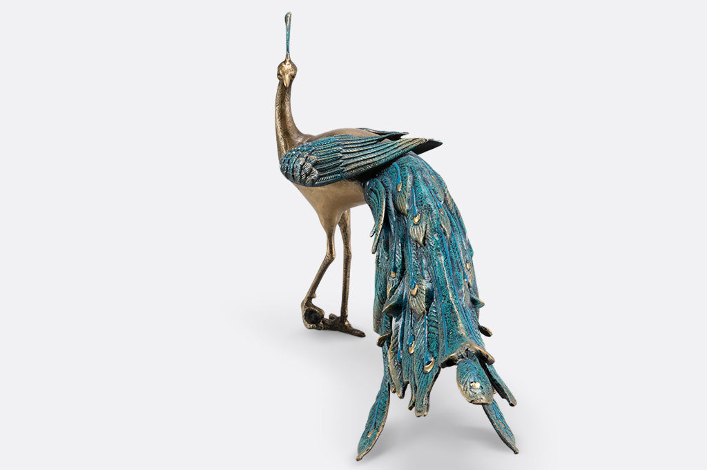 cast metal peacock with blue feathers standing proudly