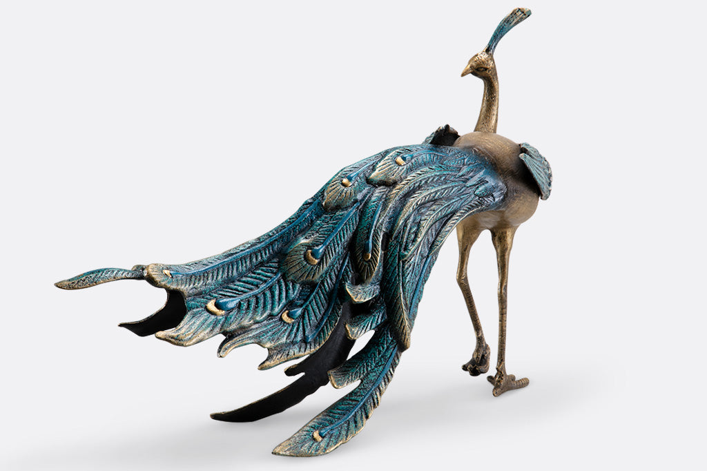 cast metal peacock with blue feathers standing proudly