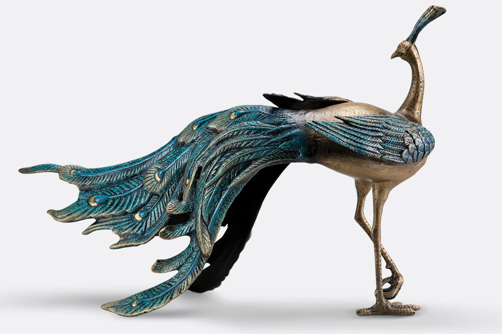 cast metal peacock with blue feathers standing proudly