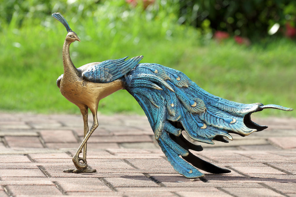 cast metal peacock with blue feathers standing proudly