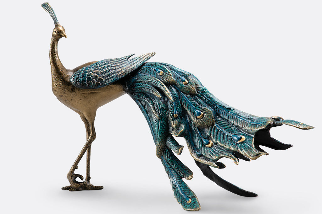 cast metal peacock with blue feathers standing proudly