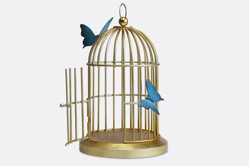 Butterflies of blue are sculpted onto a golden bird cage style plant or candle holder